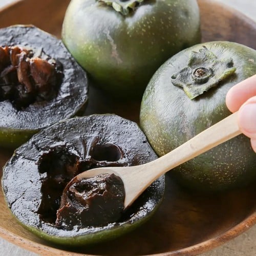Chocolate persimmon cut open, with a spoon